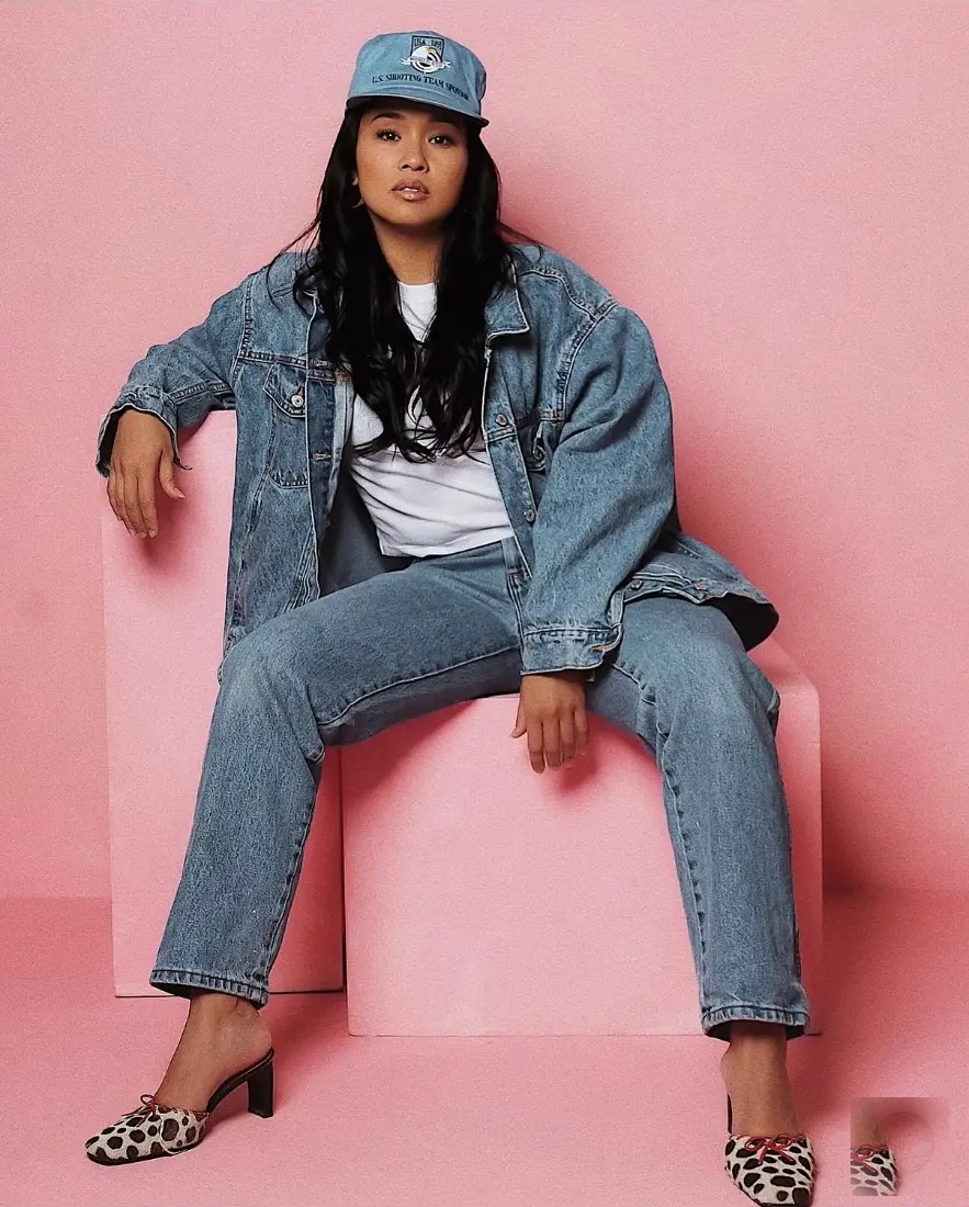 Jaylene seated in denim against a pink studio background